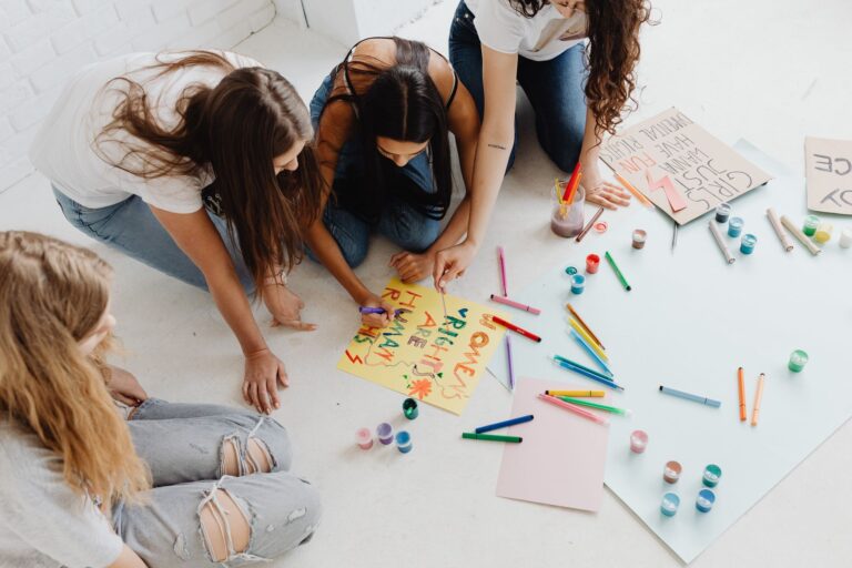 The Comfortable Radical People creating handmade protest signs with colorful materials indoors.