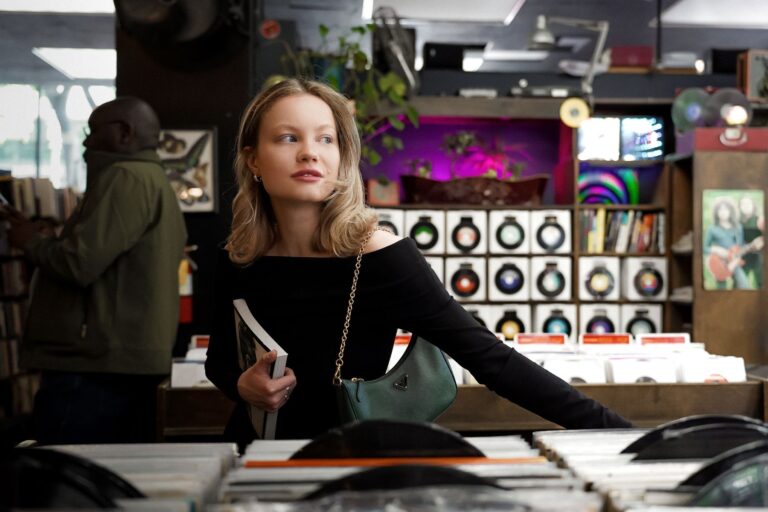 A woman browsing vinyl records in a music store, surrounded by culture for sale.